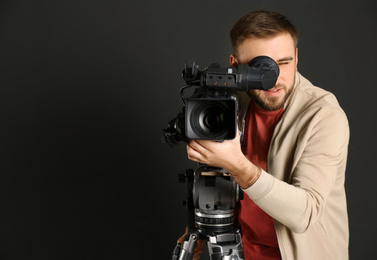 Photo of Operator with professional video camera on black background, space for text