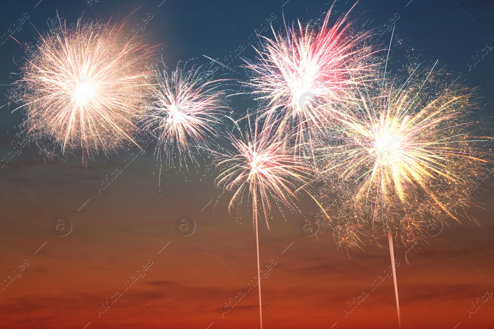 Image of Beautiful bright fireworks lighting up twilight sky outdoors