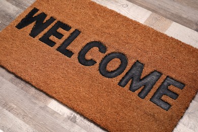 Photo of New clean mat with word WELCOME on floor, closeup