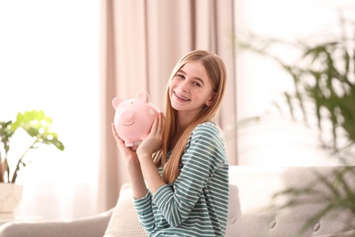Photo of Teen girl with piggy bank at home