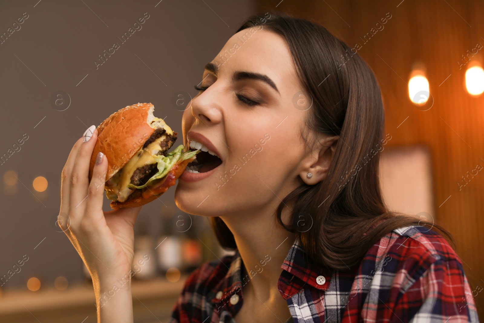 Photo of Young woman eating tasty burger in cafe