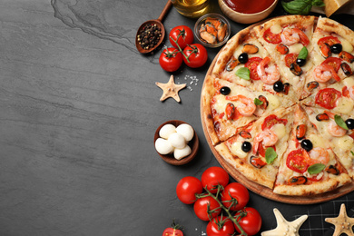 Photo of Tasty pizza with seafood and ingredients on black table, flat lay. Space for text