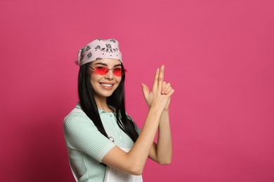 Photo of Young woman wearing stylish bandana and sunglasses on pink background, space for text