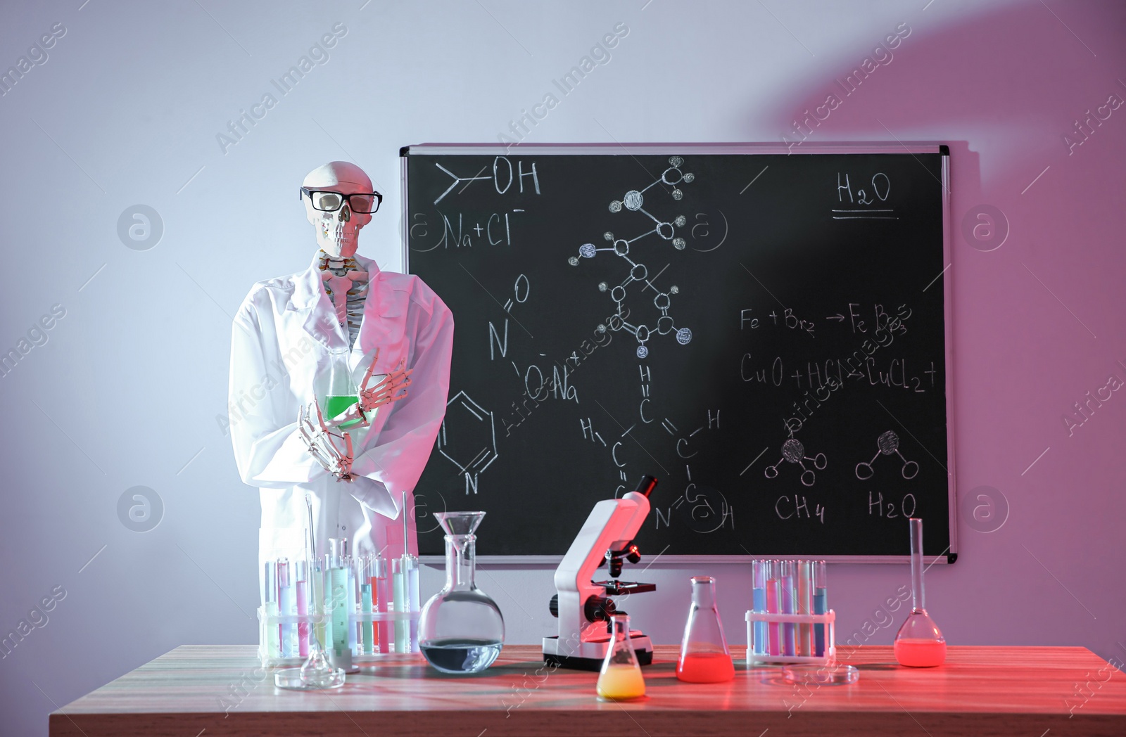 Photo of Skeleton and different chemistry glassware in classroom, toned in red