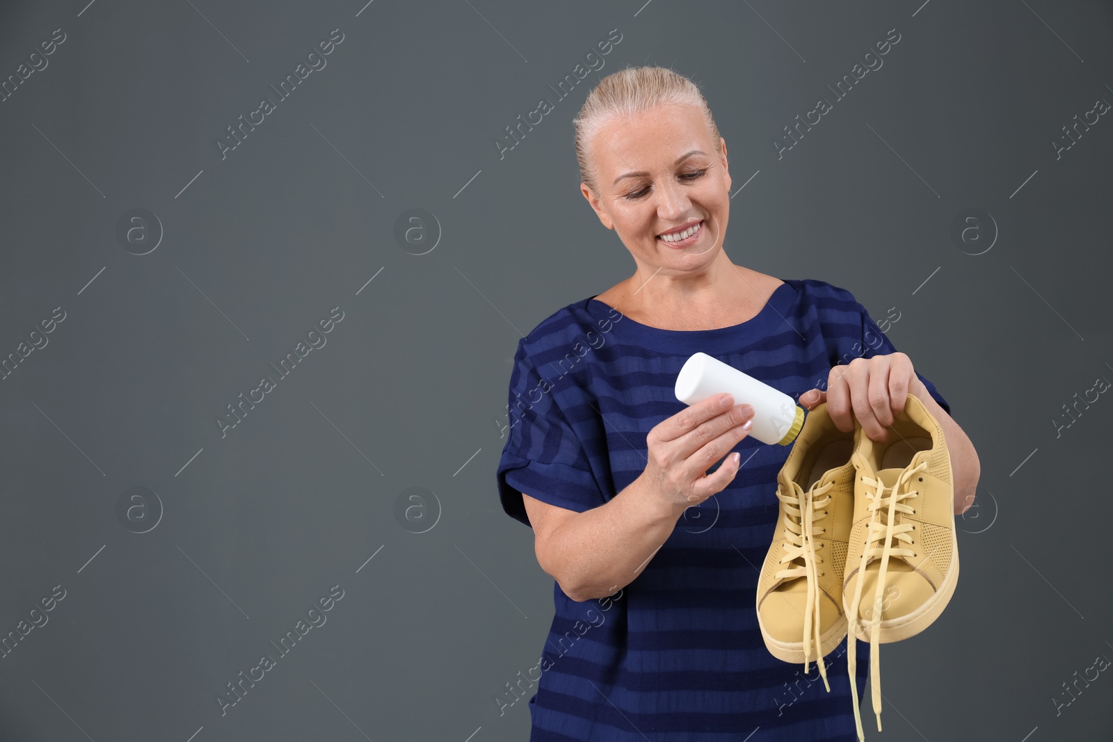 Photo of Woman putting powder shoe freshener in footwear on color background