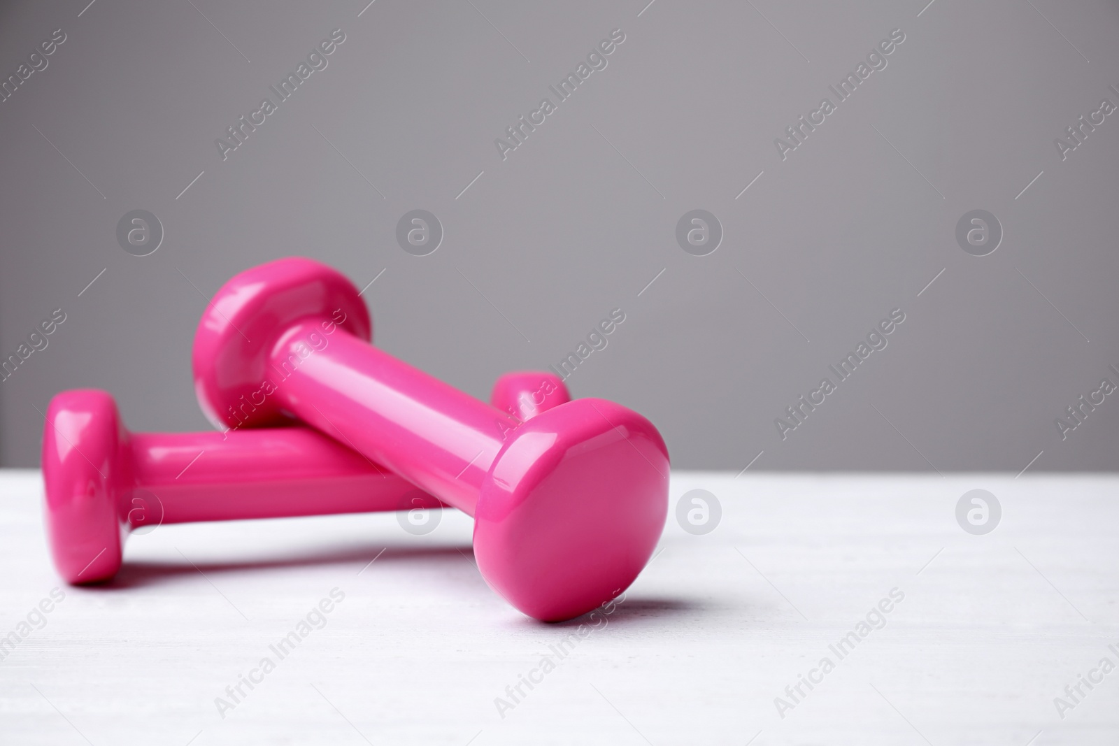 Photo of Bright dumbbells on white table, space for text. Home fitness