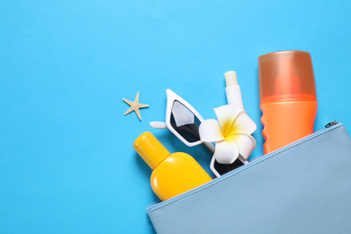 Photo of Sun protection products and sunglasses in bag on blue background