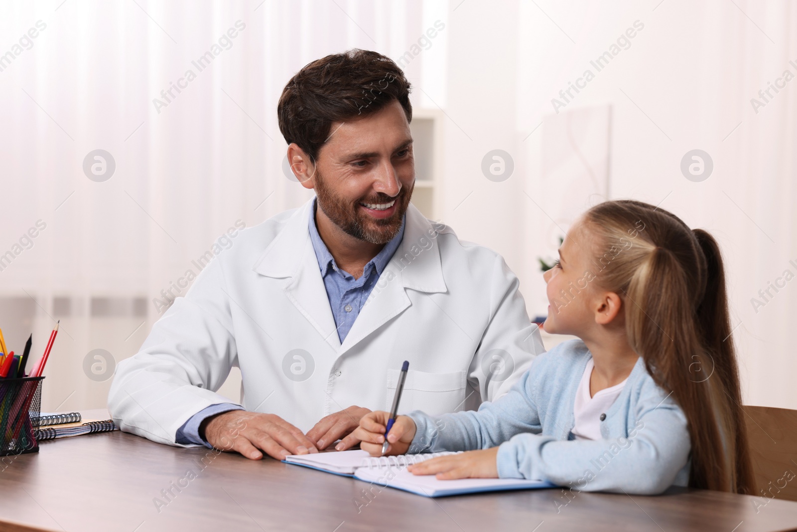 Photo of Dyslexia treatment. Therapist working with girl at table in room