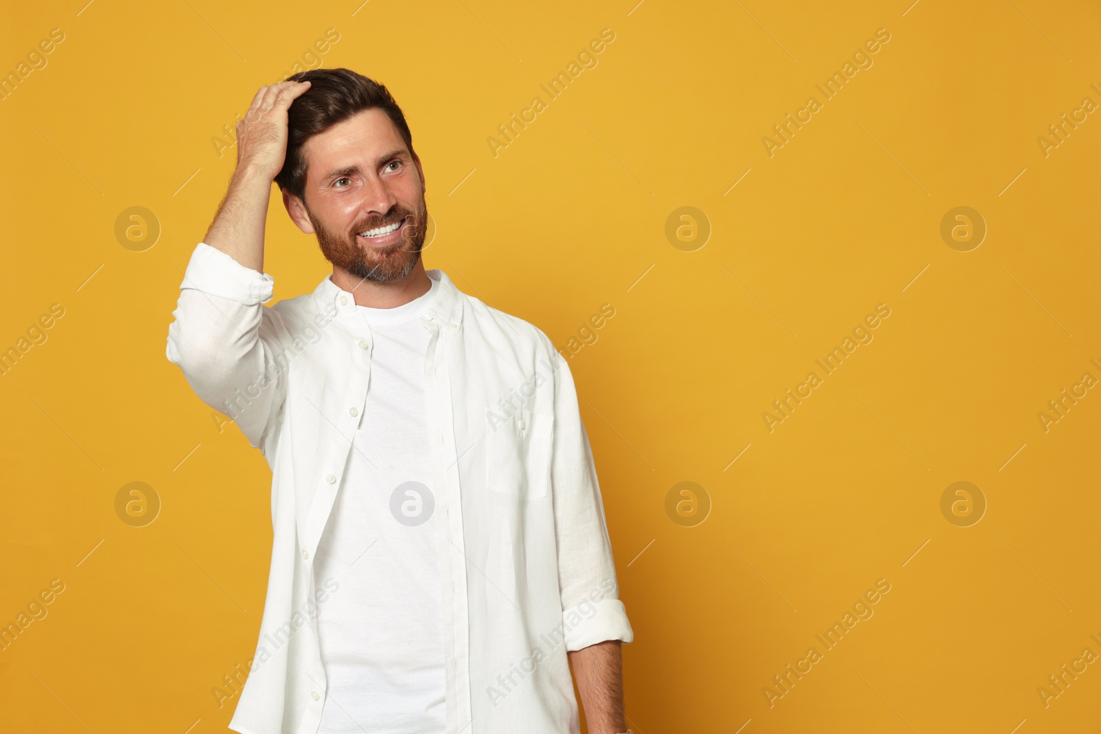 Photo of Portrait of happy bearded man on orange background. Space for text