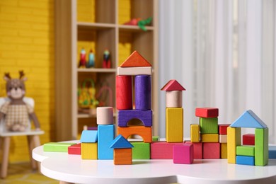 Photo of Colorful building blocks on white table in playroom