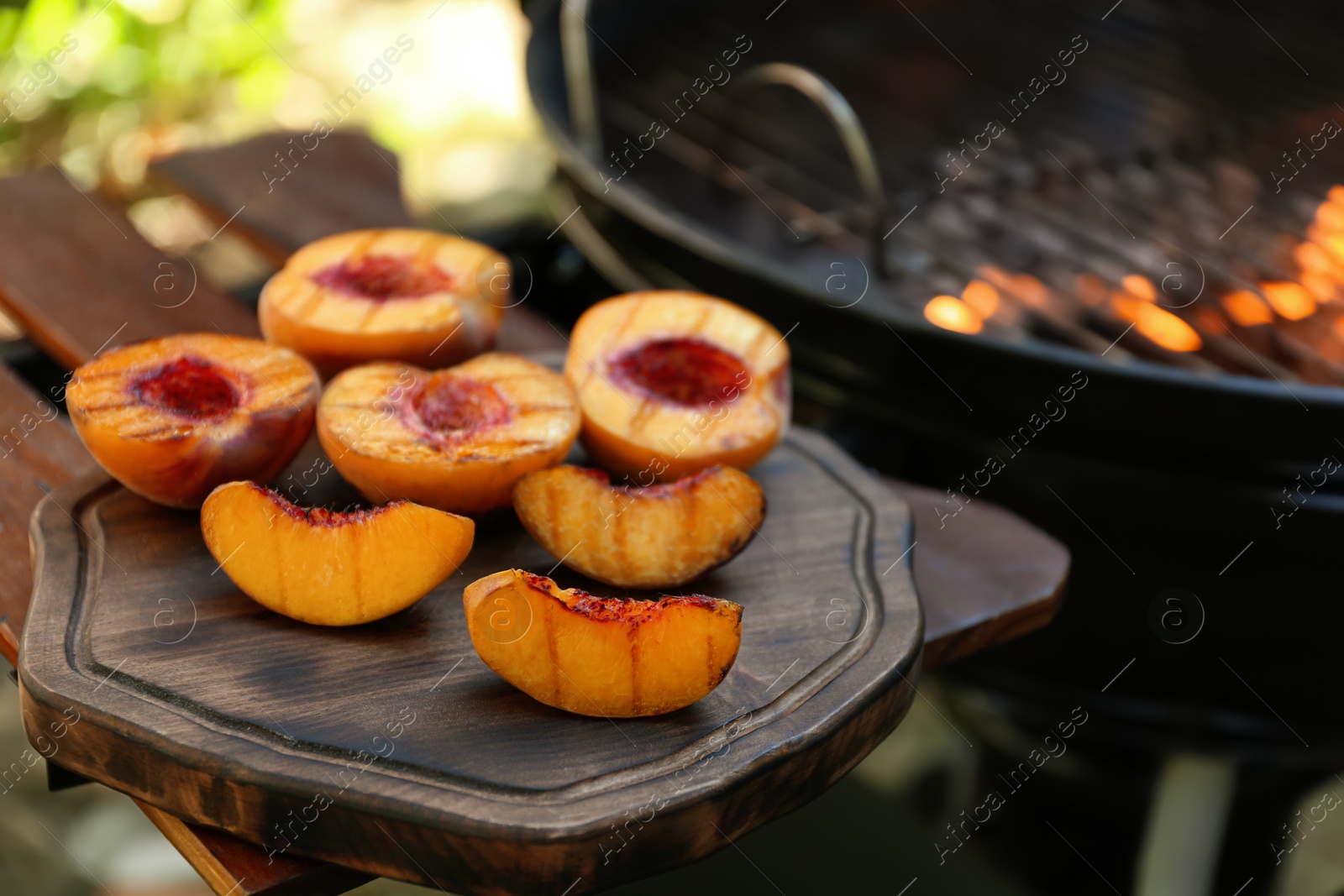 Photo of Delicious grilled peaches on wooden table outdoors, closeup