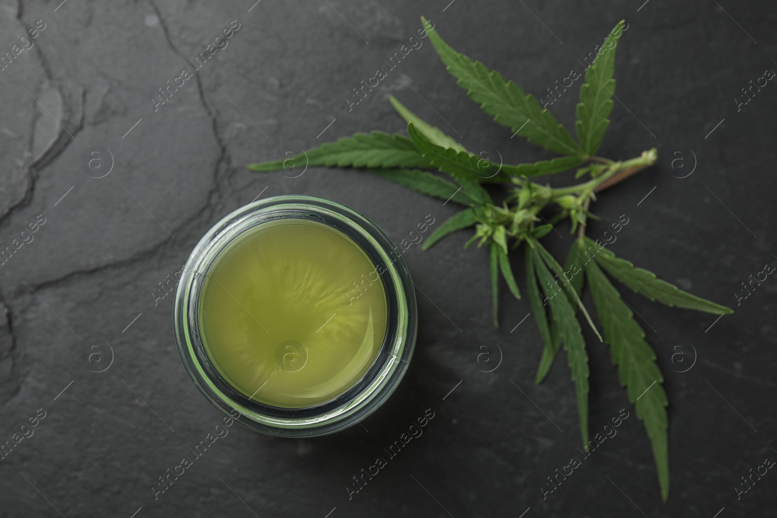 Photo of Jar of hemp cream on dark stone table, flat lay. Organic cosmetics