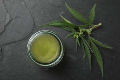 Jar of hemp cream on dark stone table, flat lay. Organic cosmetics