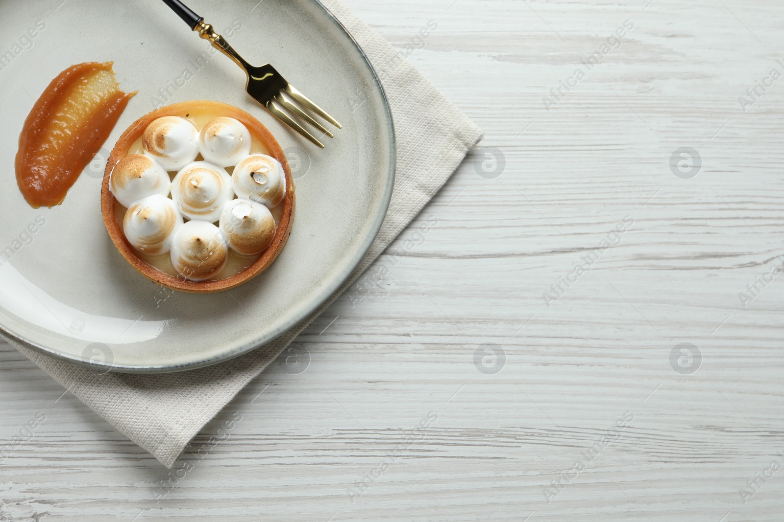 Photo of Tartlet with meringue served on white wooden table, top view and space for text. Delicious dessert