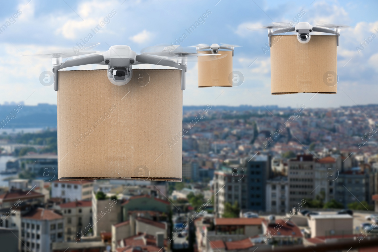 Image of Modern drones with carton boxes flying above city on sunny day. Delivery service 