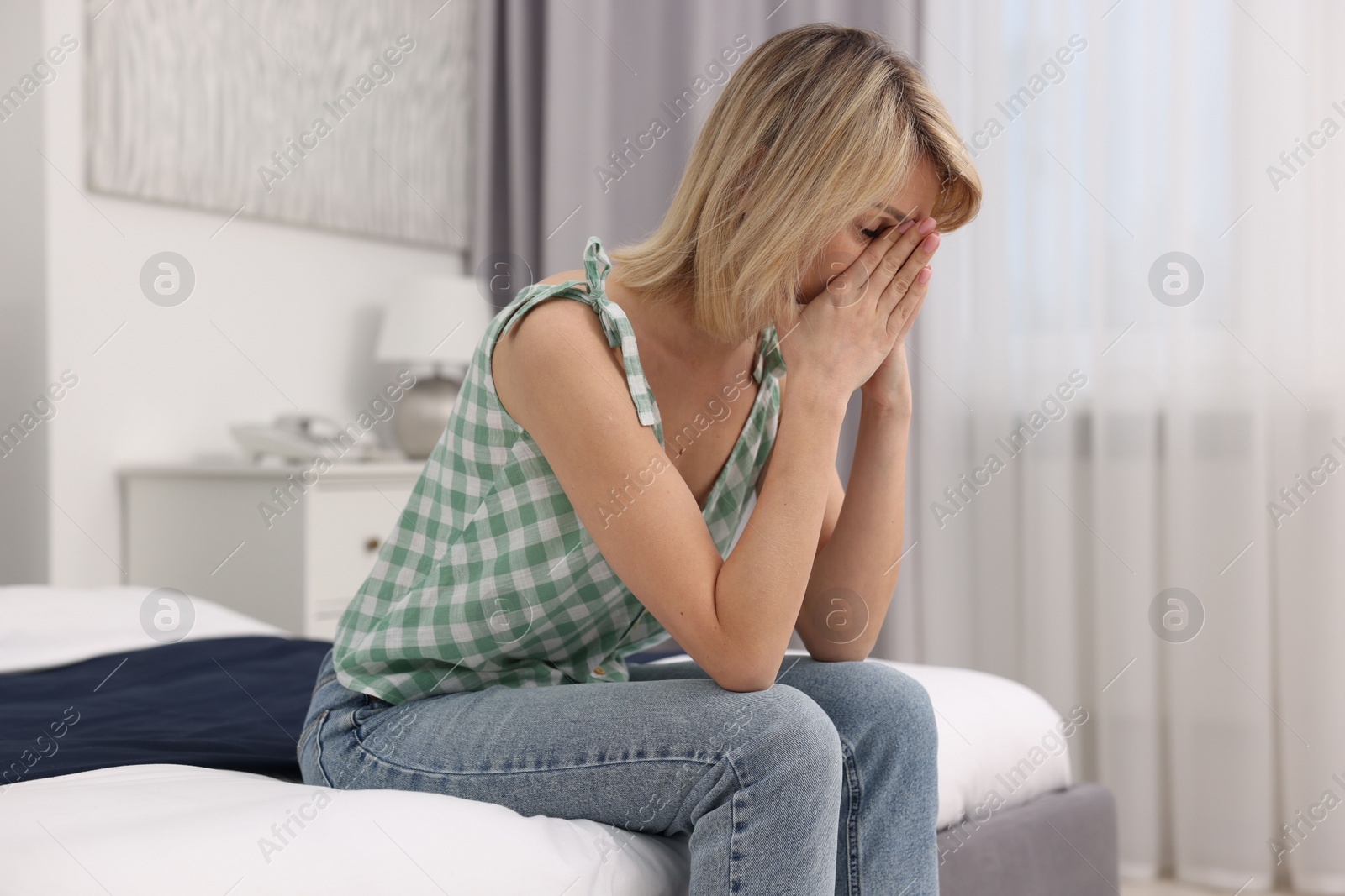 Photo of Overwhelmed woman covering face with hands at home