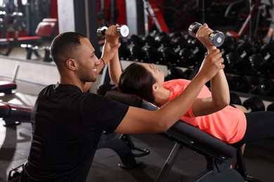 Photo of Young woman working out with professional trainer in modern gym