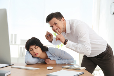 Man drawing on colleague's face while she sleeping at workplace. April fool's day