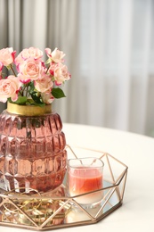 Vase with beautiful flowers and candle on white table indoors, closeup. Interior elements
