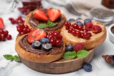 Photo of Tasty organic rusks with different toppings and ingredients on white marble table, closeup