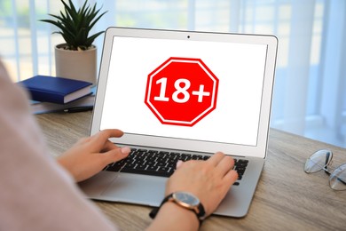 Image of Woman using laptop with age limit sign 18+ years indoors, closeup
