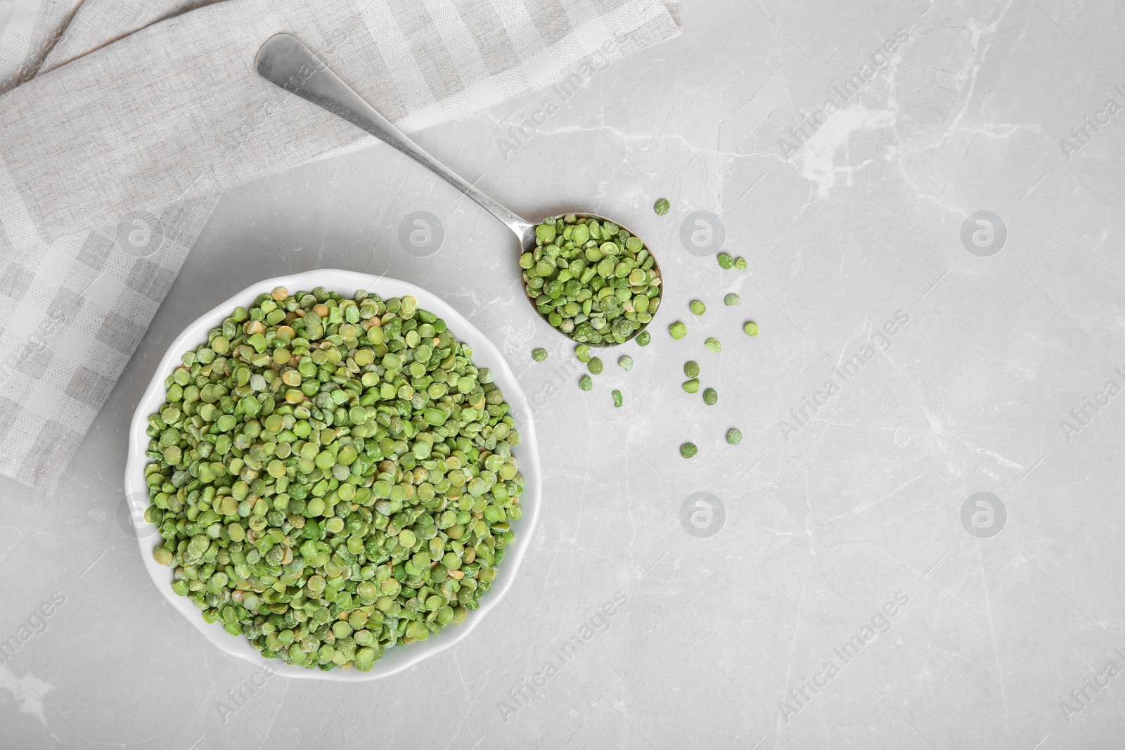 Photo of Bowl and spoon with dried peas on light background, top view