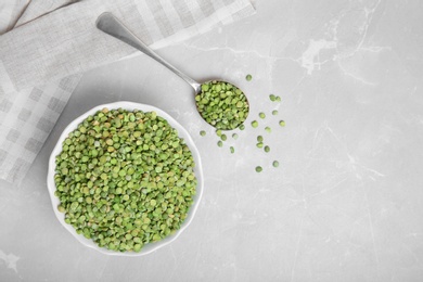 Bowl and spoon with dried peas on light background, top view