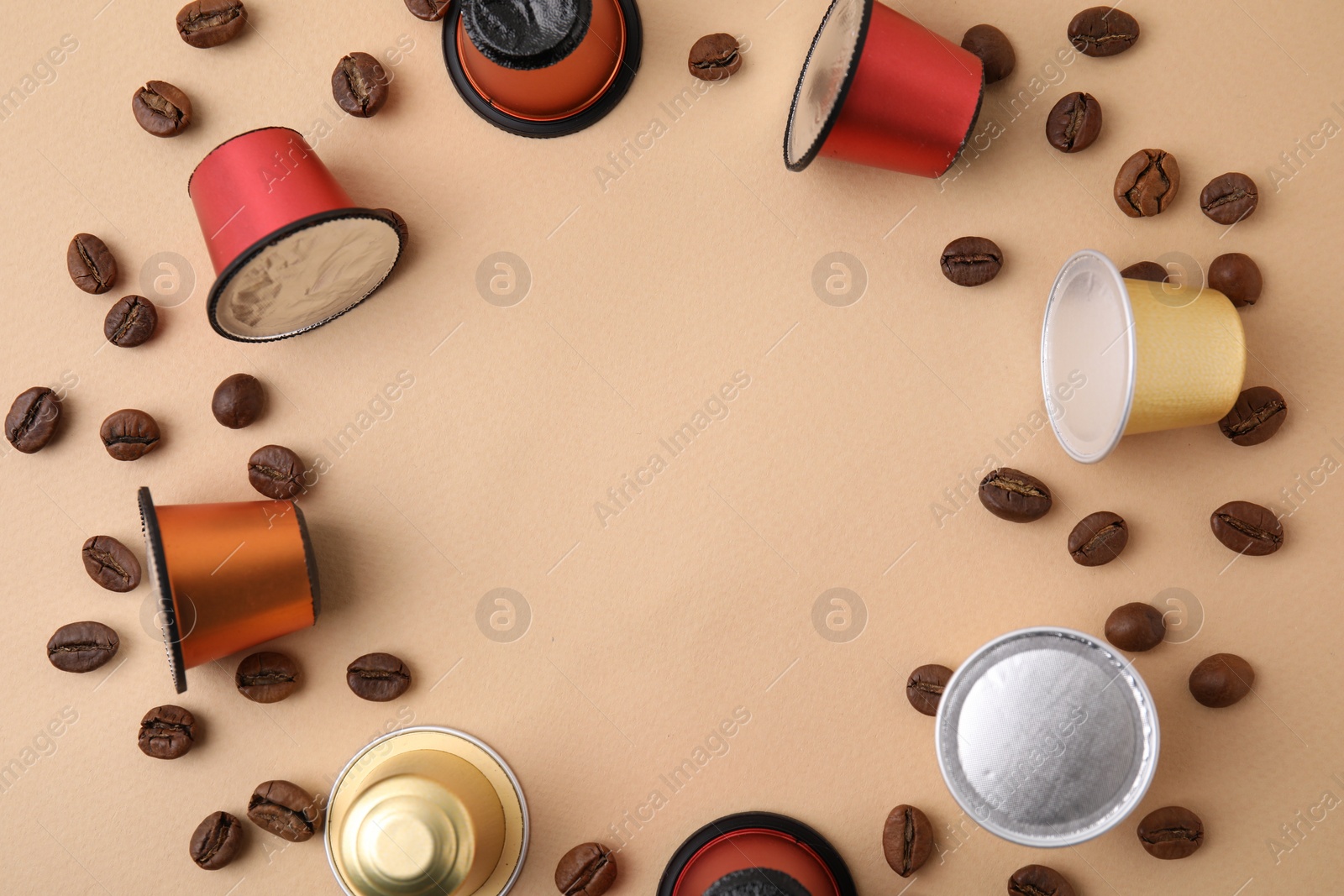 Photo of Frame made of many coffee capsules and beans on beige background, top view. Space for text