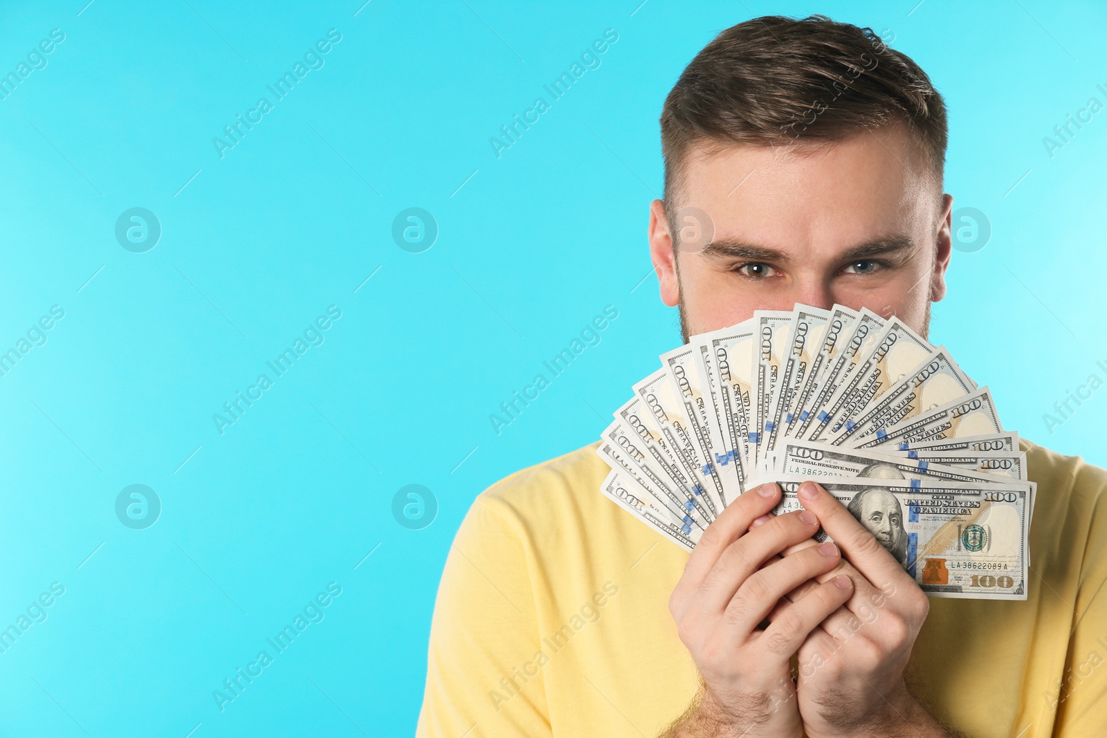 Photo of Happy young man with money on color background. Space for text