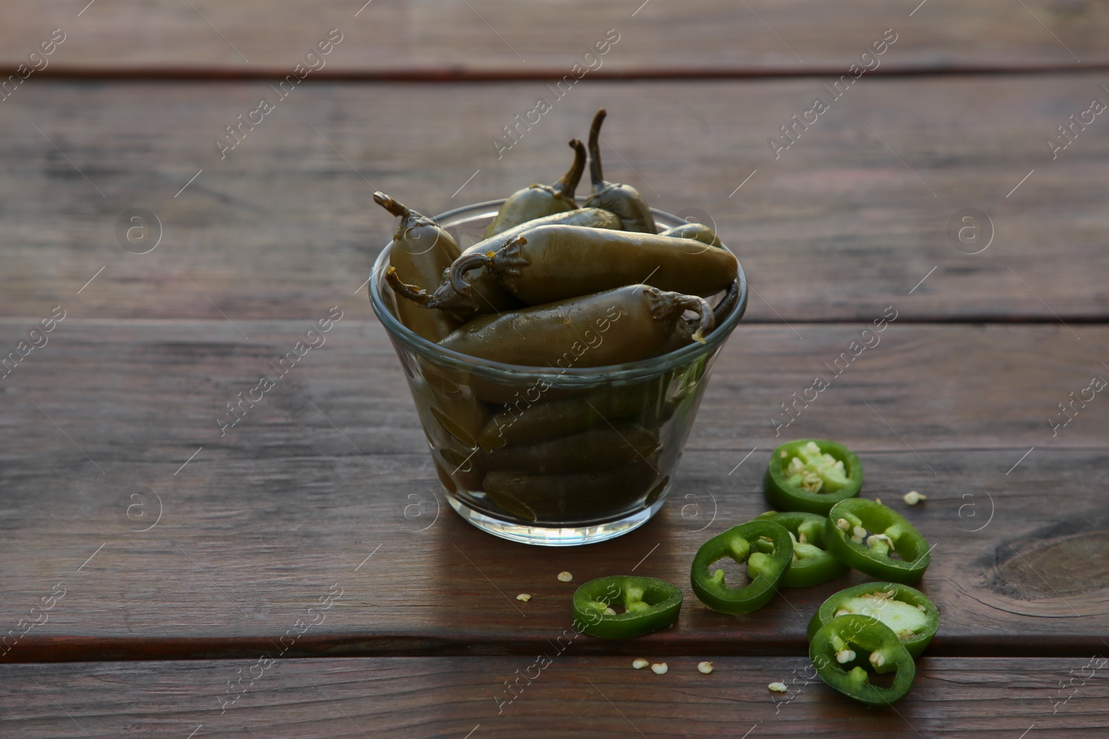 Photo of Fresh and pickled green jalapeno peppers on wooden table