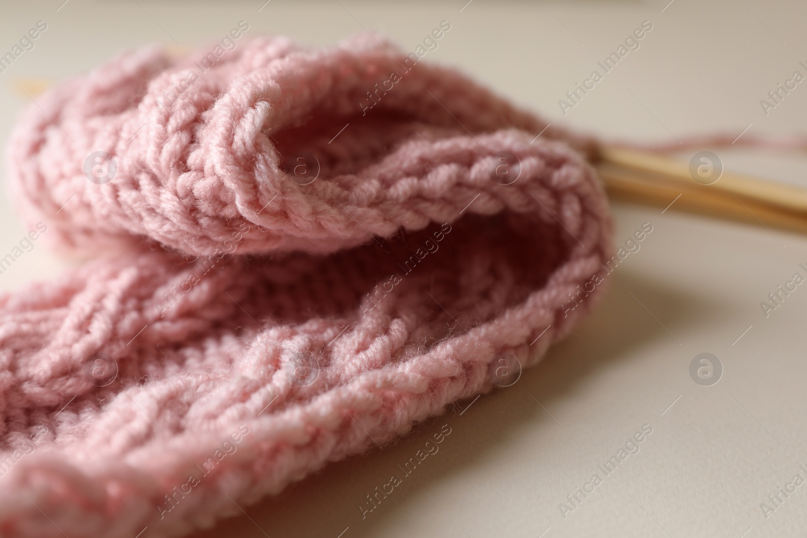 Photo of Pink knitting and needles on beige background, closeup