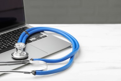 Stethoscope and modern laptop on white table. Space for text