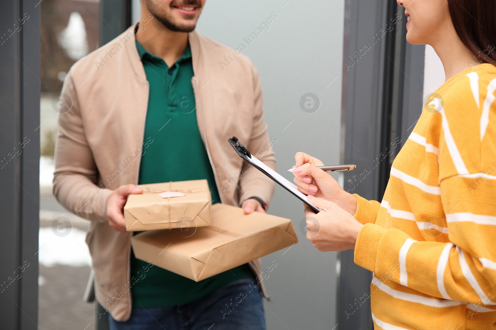 Photo of Woman receiving parcels from delivery service courier indoors, closeup