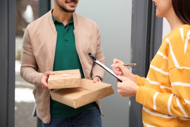 Woman receiving parcels from delivery service courier indoors, closeup