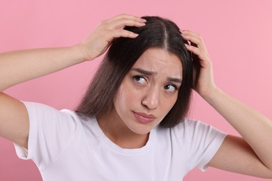 Photo of Emotional woman suffering from dandruff problem on pink background