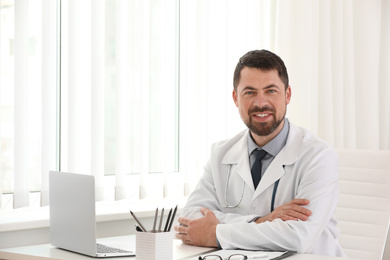 Portrait of male doctor in white coat at workplace