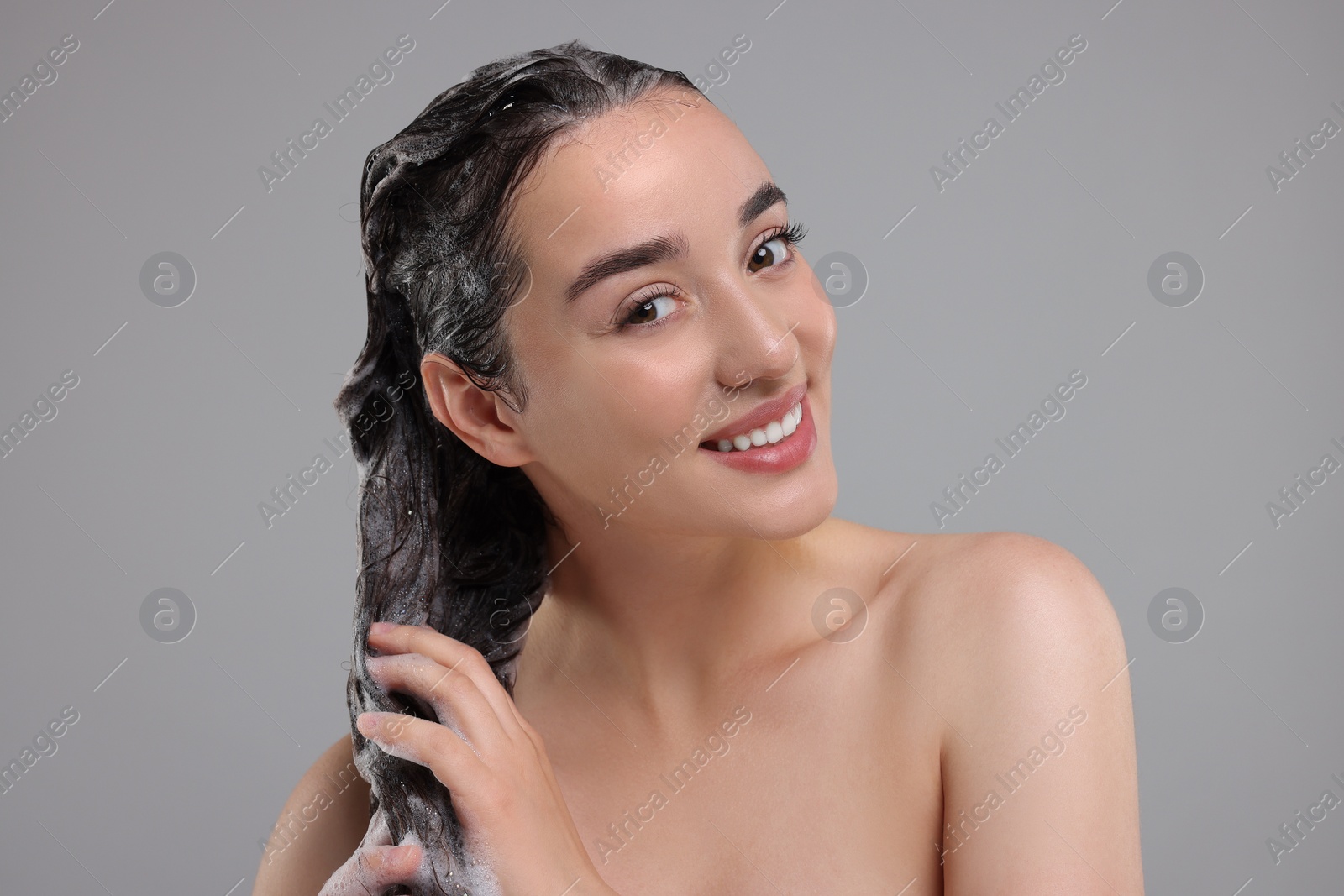 Photo of Portrait of beautiful happy woman washing hair on grey background