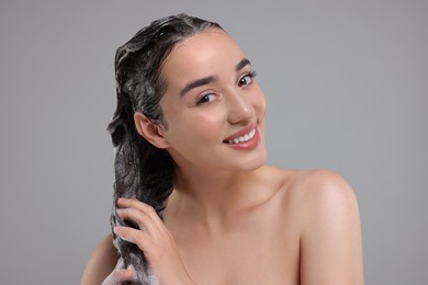 Photo of Portrait of beautiful happy woman washing hair on grey background