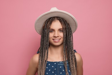 Photo of Beautiful woman with long african braids and hat on pink background
