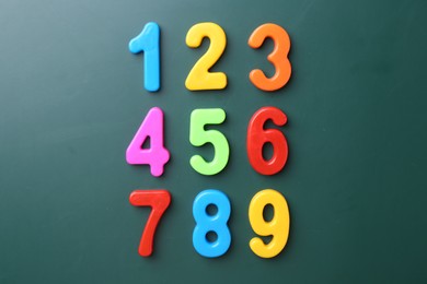 Colorful numbers on green background, flat lay