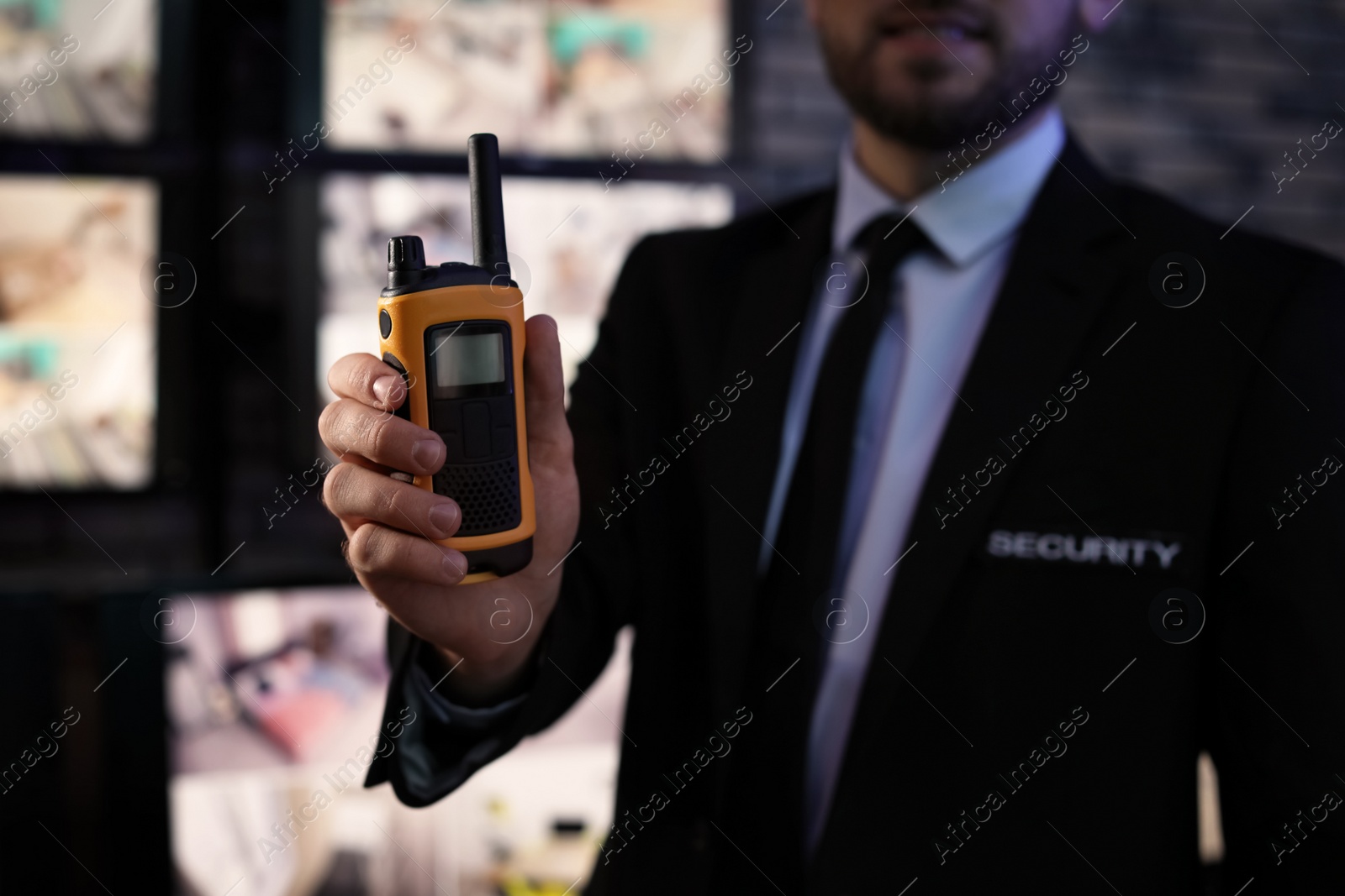 Photo of Male security guard with portable transmitter near cameras indoors, closeup