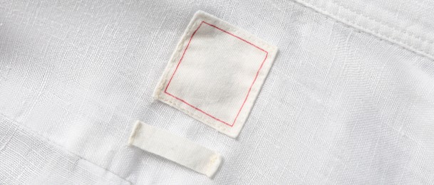 Blank clothing labels on white shirt, top view. Banner design