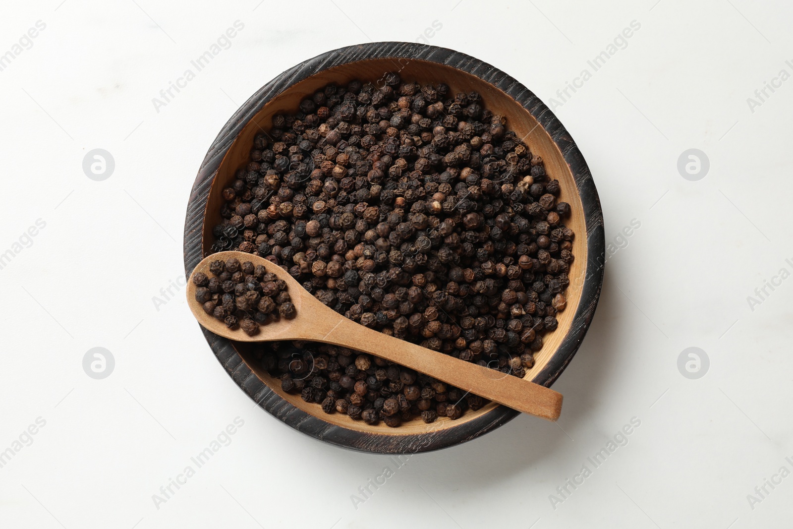 Photo of Aromatic spice. Black pepper in bowl and spoon on white table, top view