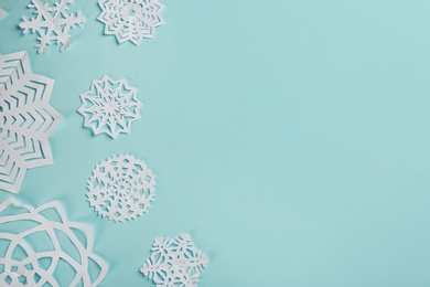 Photo of Flat lay composition with paper snowflakes on cyan background. Space for text