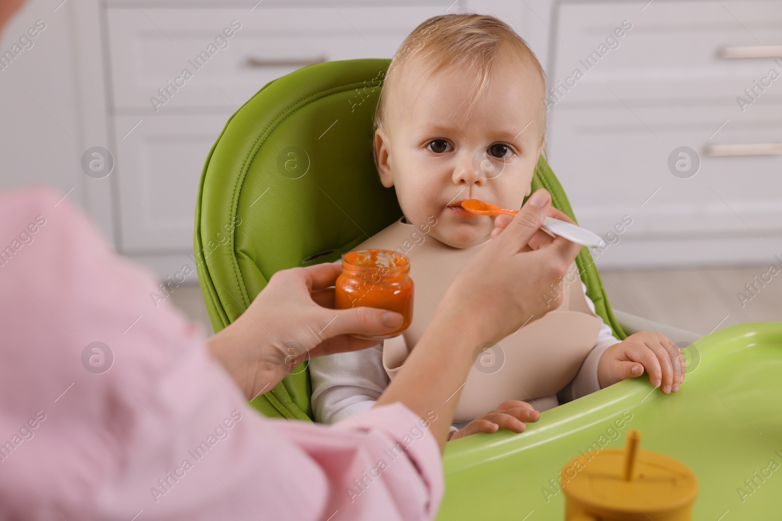 Photo of Mother feeding her cute little baby with healthy food at home