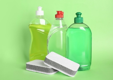 Photo of Different detergents and sponges on green background
