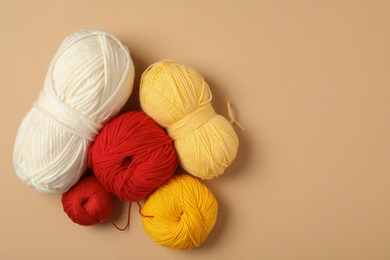 Photo of Soft woolen yarns on beige background, flat lay. Space for text