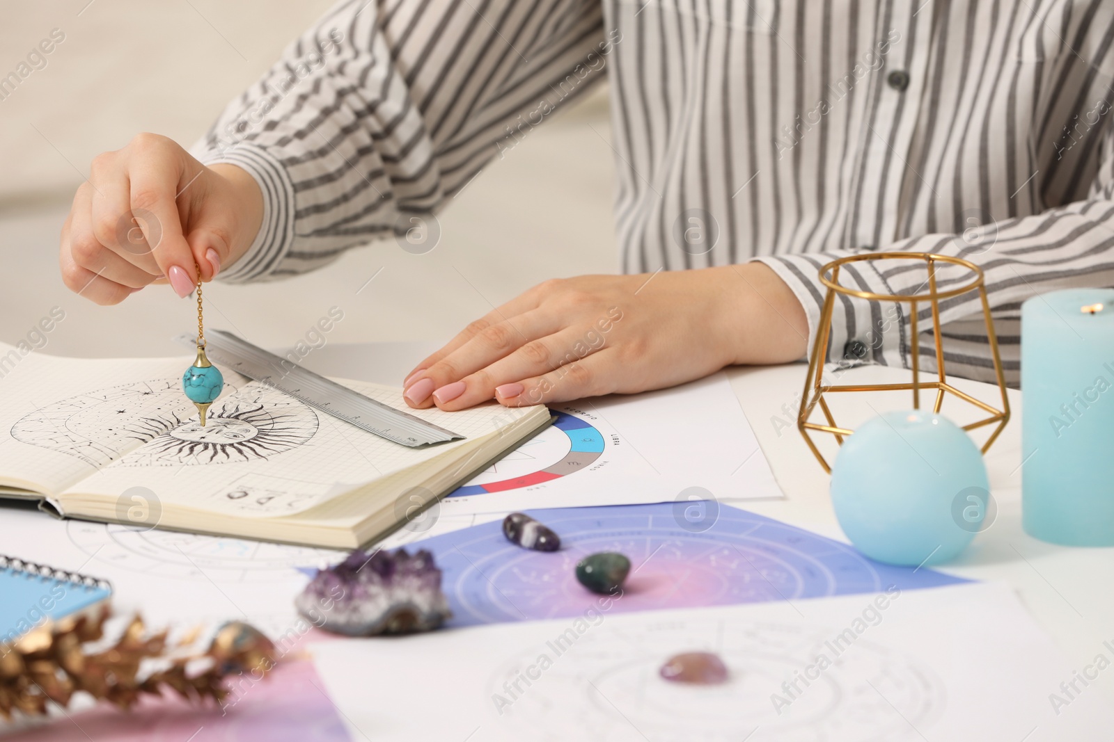 Photo of Astrologer using zodiac wheel and pendulum for fate forecast at table, closeup. Fortune telling