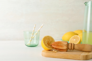 Board with lemon half and wooden juicer on table. Space for text