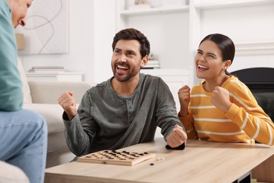 Family enjoying winning after play checkers at home
